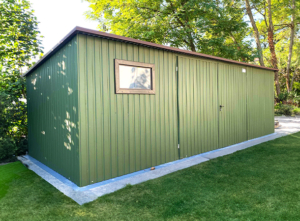 7x3m-es sztenderd tároló hátra lejtő tetővel, kétszárnyú kapuval, ablakkal, szegélyezéssel, sötétzöld színben